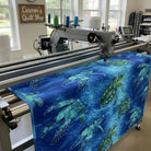 Carmon's Quilt Shop sea turtle patterned 108-inch cotton fabric being machine quilted on a longarm frame