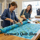 Carmon's Quilt Shop staff cutting blue sea turtle patterned 108-inch cotton quilting fabric on a wooden table.