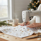 Carmon's Quilt Shop Snowbound White Ornaments cotton fabric being sewn on a machine with festive holiday decor