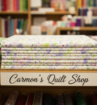 Carmon's Quilt Shop Sally's Speckle paint splatter 108-inch wide cotton backing fabric folded on a store shelf.