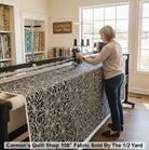 Carmon's Quilt Shop 108-inch black cotton fabric with white spiderweb print on a longarm quilting machine