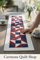 Stars & Ribbons quilted table runner in red, white, and blue by Carmon's Quilt Shop on a wooden dining table