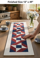 Carmon's Quilt Shop Stars & Ribbons table runner featuring red, white, and blue star blocks on a wooden dining table.