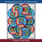 Carmon's Quilt Shop Stonehenge Beauty quilt featuring a vibrant paper-pieced star design in blue, green, and pink tones.