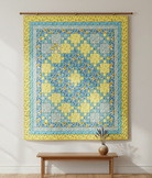 Carmon's Quilt Shop Sunny Skies quilt kit featuring a yellow and blue floral patchwork design hanging on a wall.