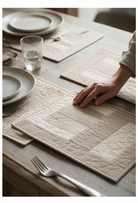 Carmon's Quilt Shop Table for Four placemats in neutral beige tones with quilted patchwork detail on a wooden table.