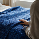 Carmon's Quilt Shop Mystique Blender ultramarine blue cotton fabric with ornate paisley motifs on a quilted bedspread