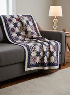 Carmon's Quilt Shop Fabric Café Vintage quilt featuring a red, white, and blue star pattern draped over a grey sofa.
