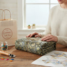 Carmon's Quilt Shop Walnut Phantasma fabric features a geometric starburst hexagon pattern in gold, grey, and black. 100% cotton, 108" wide.